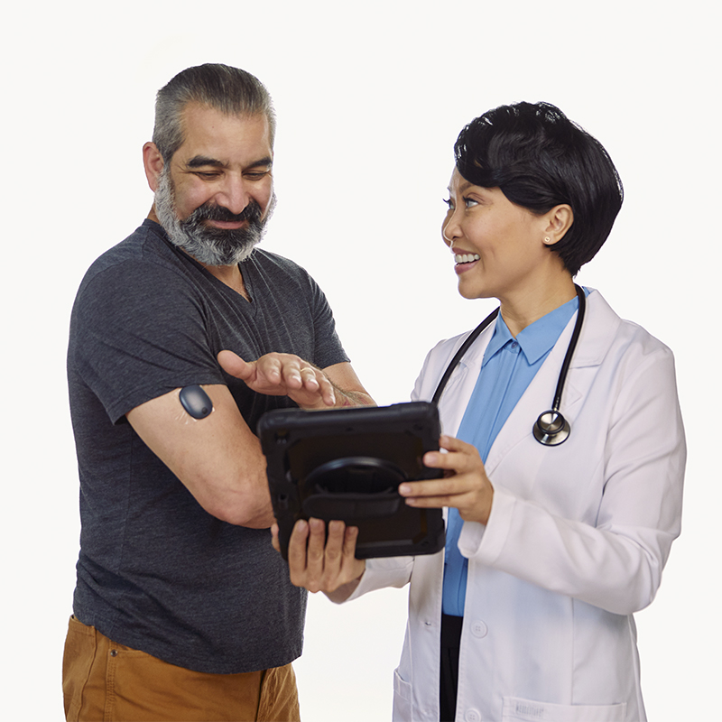 Een zorgverlener laat een patiënt op een tablet zien hoe glucosegegevens van een implanteerbare cgm kunnen worden bijgehouden.