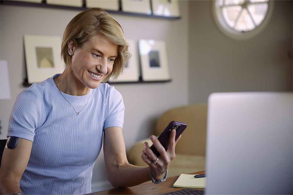 Vrouw zoekt op haar telefoon naar de verzekeringsdekking voor een implanteerbare CGM.
