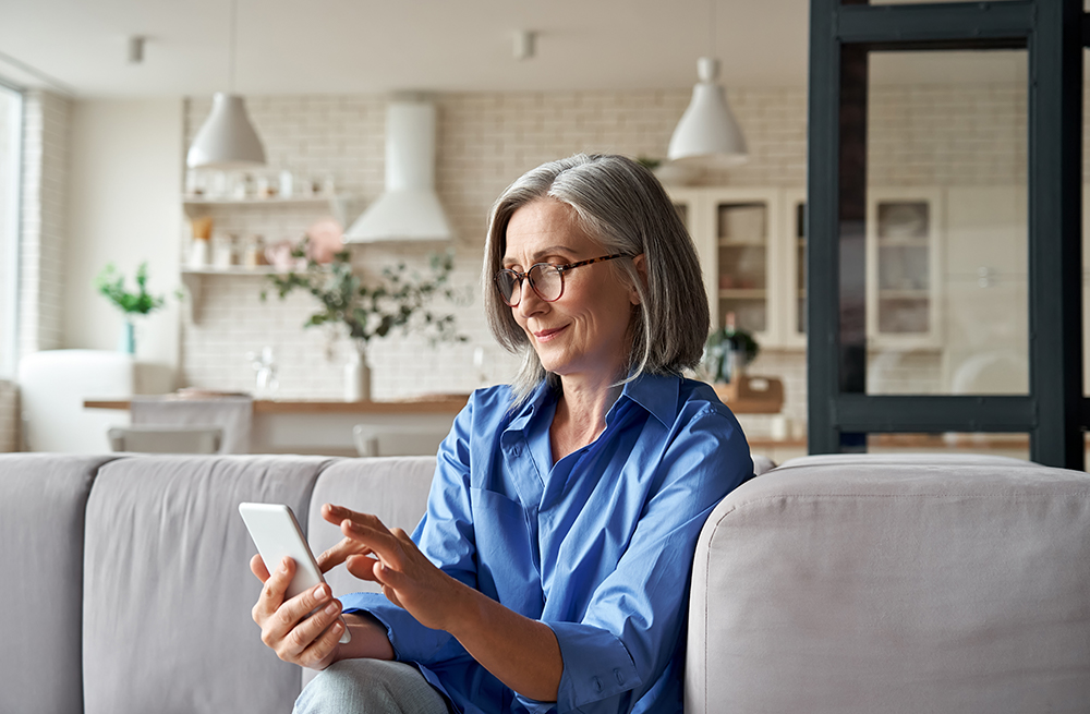 Vrouw zoekt op een mobiele telefoon meer informatie over de kosten van de Eversense E3 CGM.