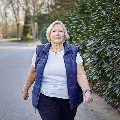 Vrouw wandelt buiten en draagt haar Eversense CGM met glucosesensortechnologie.